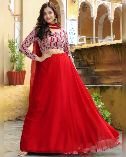 Woman wearing a red and white traditional outfit in an outdoor setting with architectural elements.