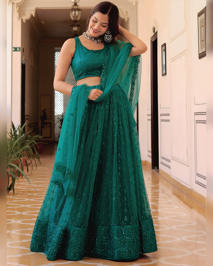 Woman in a teal traditional outfit standing in a hallway.