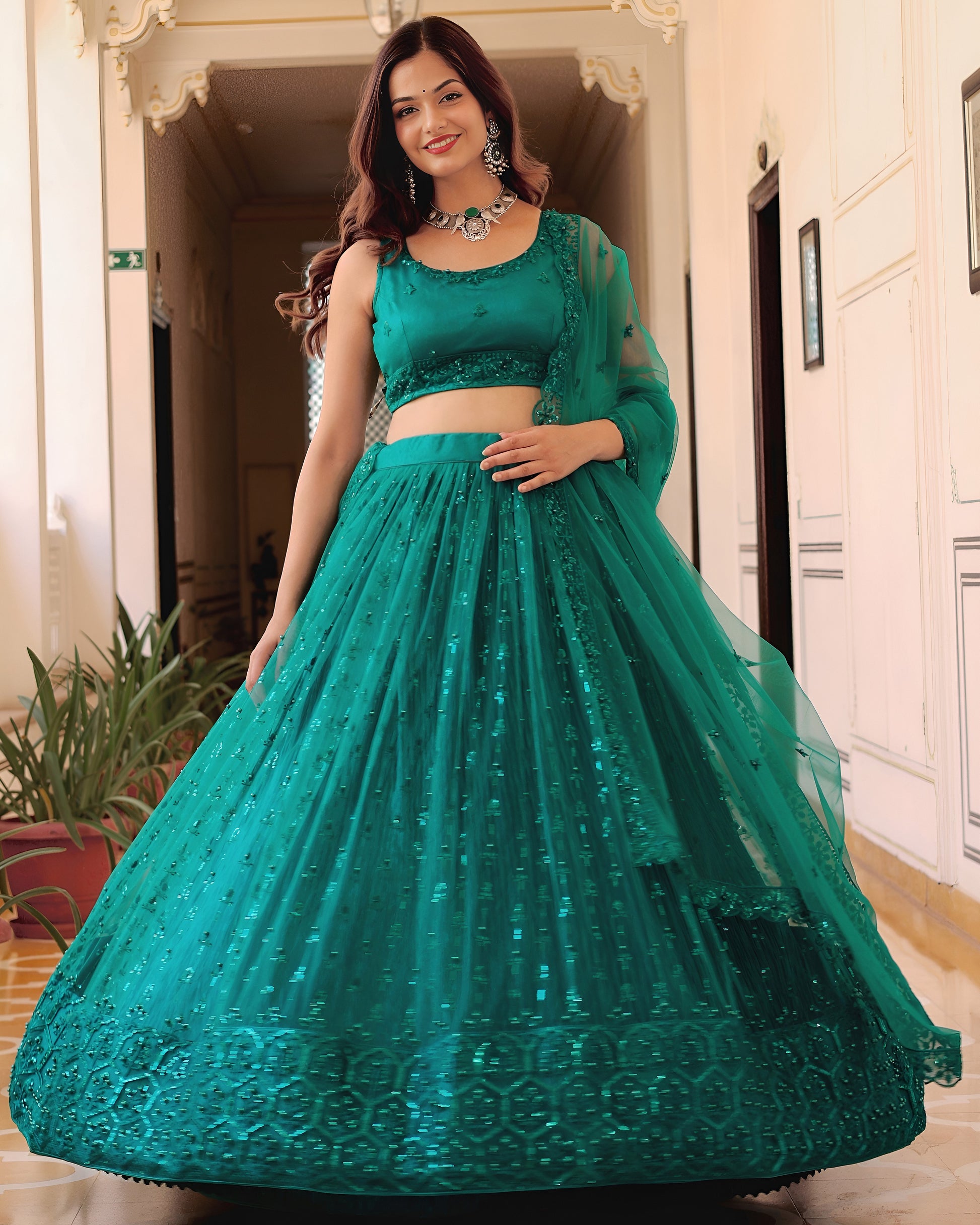 Woman wearing a teal embroidered outfit indoors