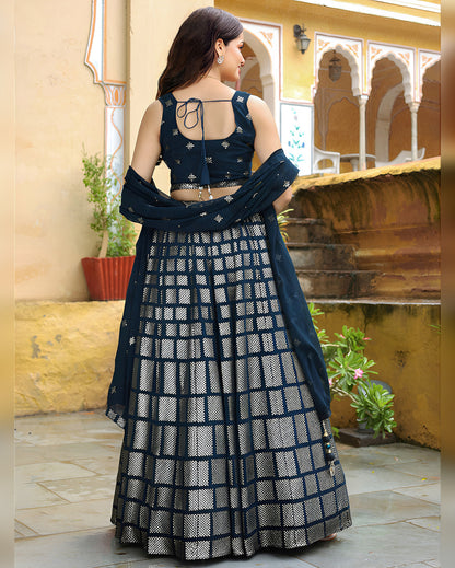 Woman wearing a dark blue and white patterned traditional outfit in an outdoor setting.