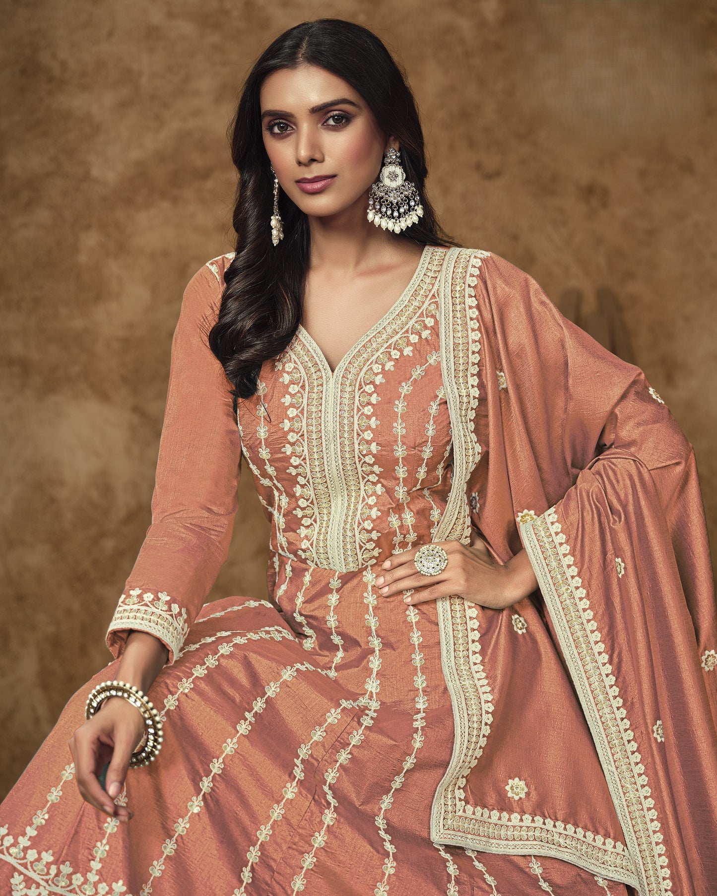 Woman wearing a traditional pink and white embroidered outfit with a brown background