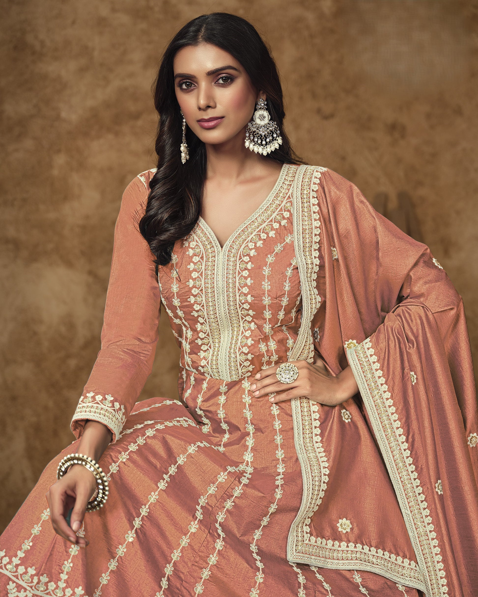 Woman wearing a traditional pink and white embroidered outfit with a brown background