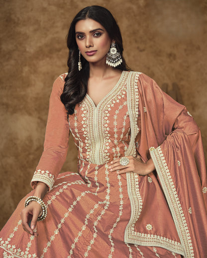 Woman wearing a traditional pink and white embroidered outfit with a brown background