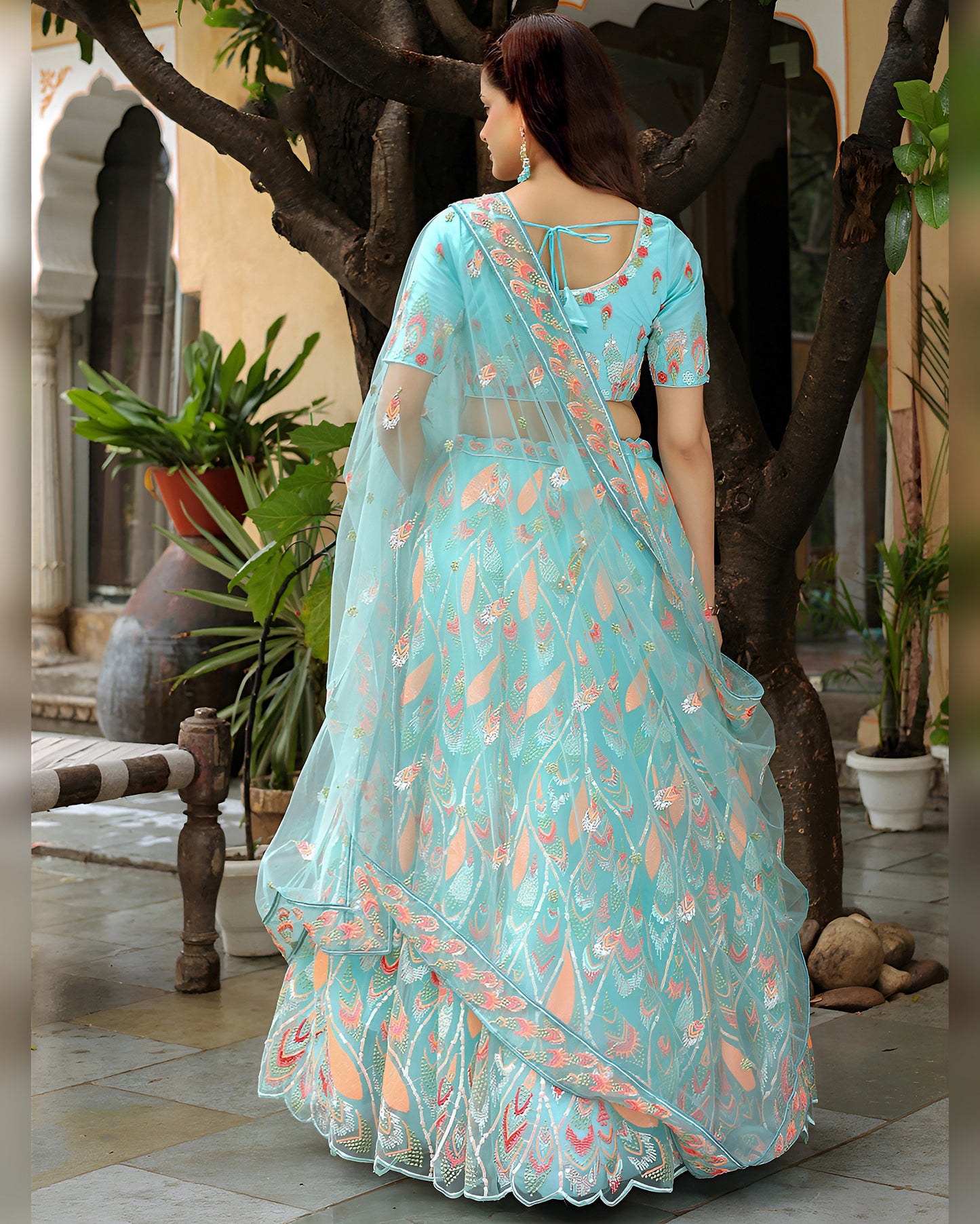 Woman in a light blue saree with floral patterns standing in an outdoor setting.