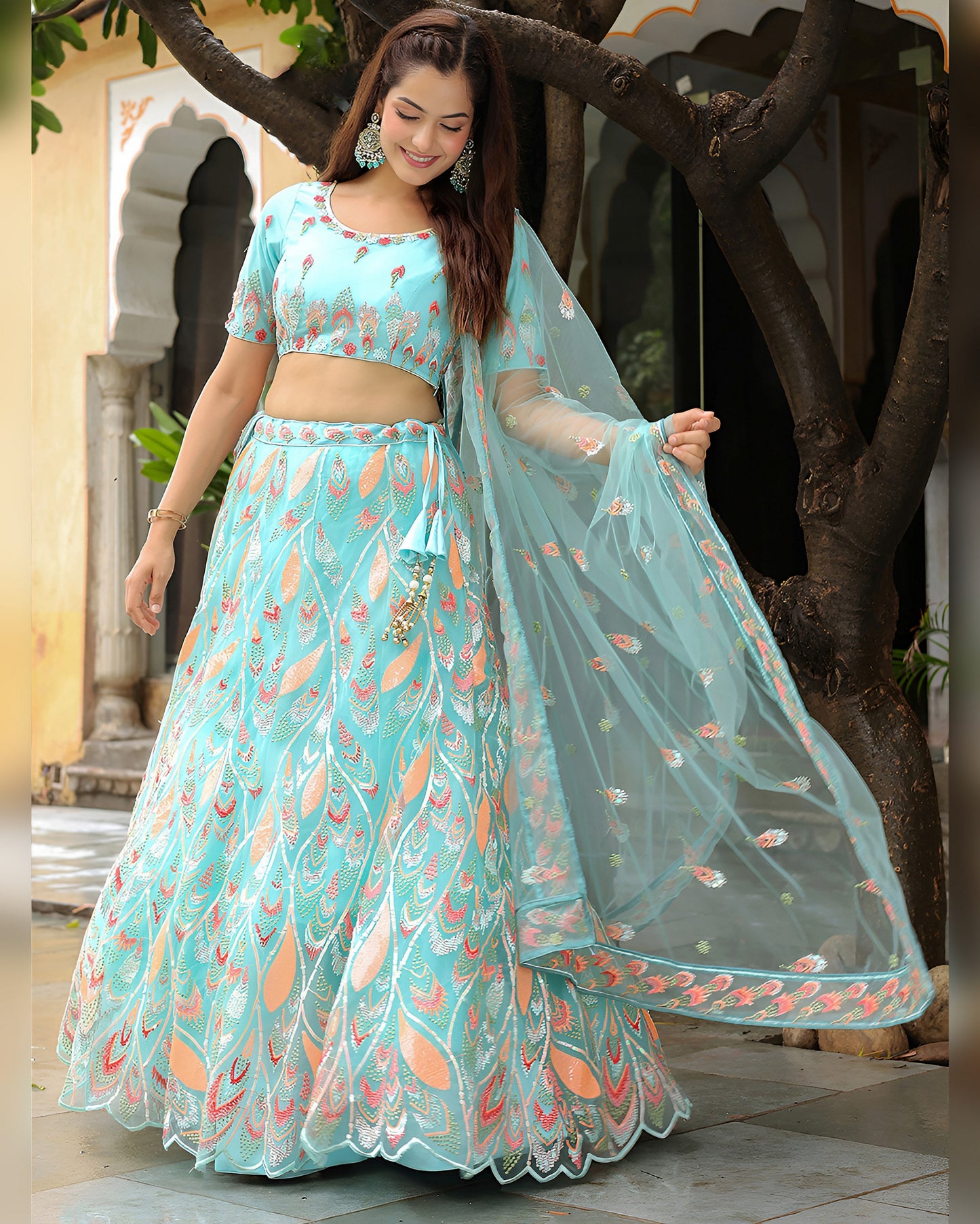 Woman in a light blue traditional outfit with floral patterns outdoors.