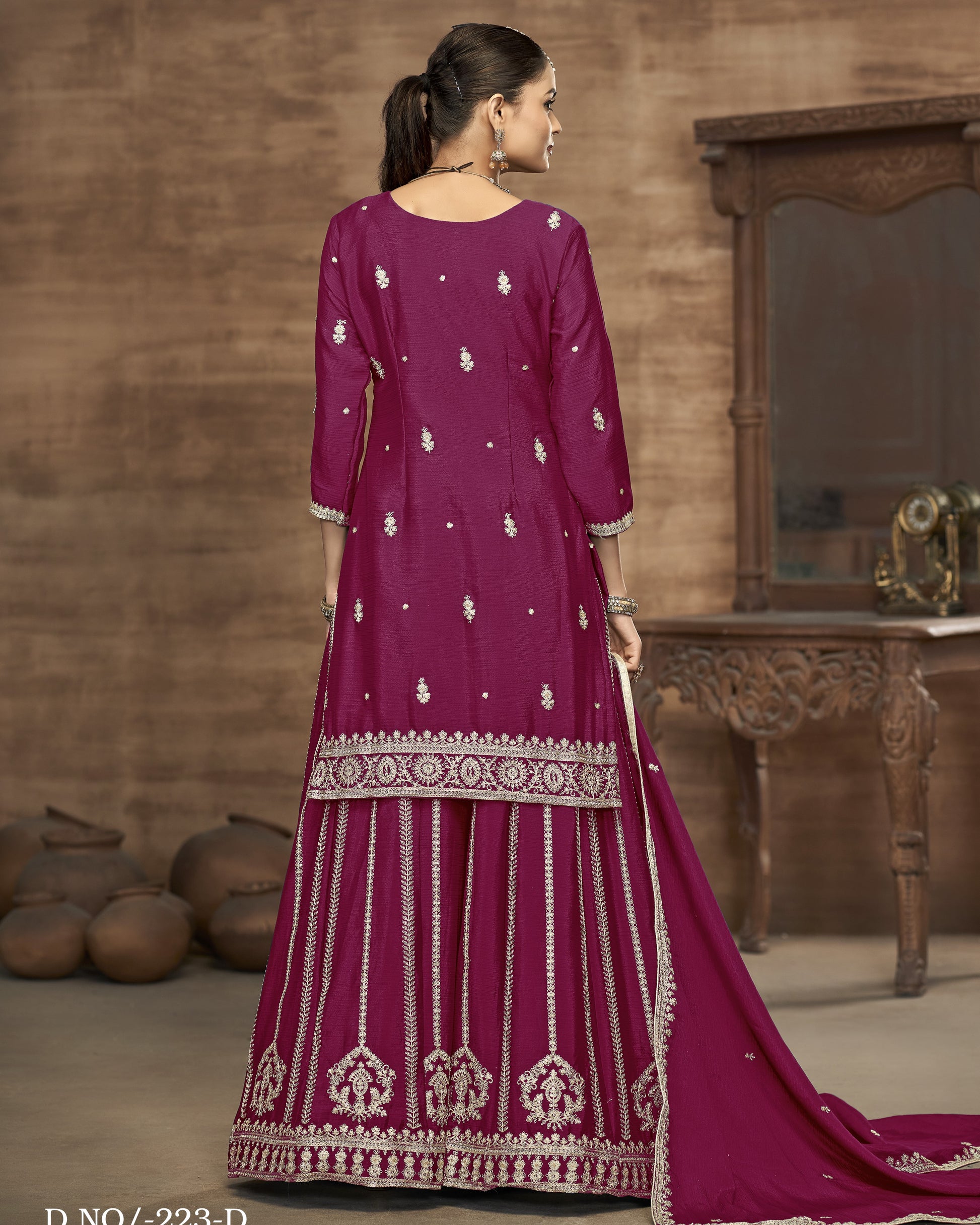 Woman wearing a magenta traditional outfit with white embroidery in a rustic setting