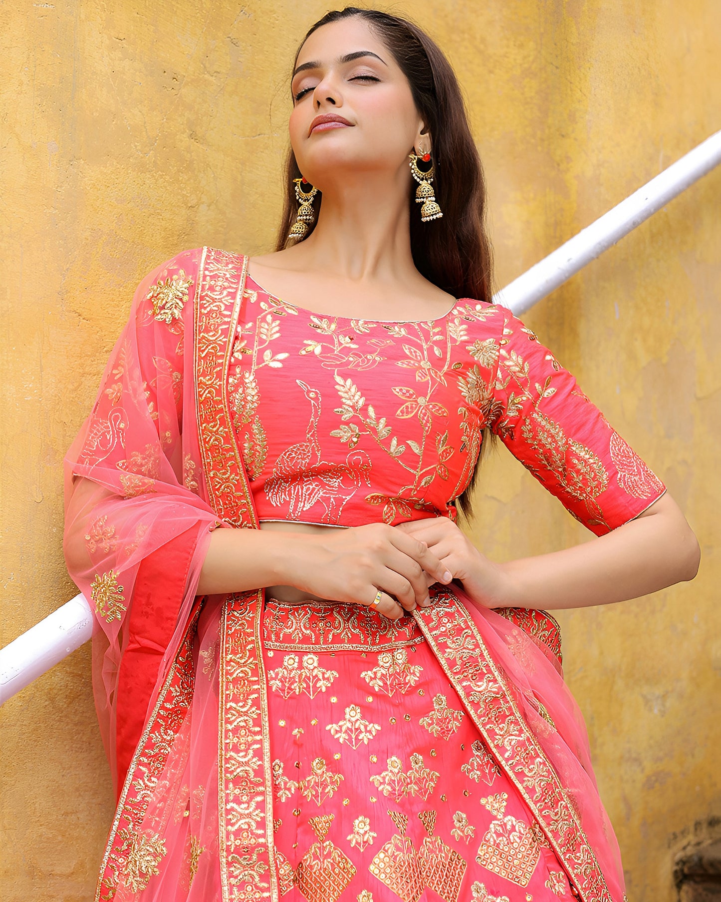 Woman wearing a pink traditional outfit with gold embroidery against a yellow background