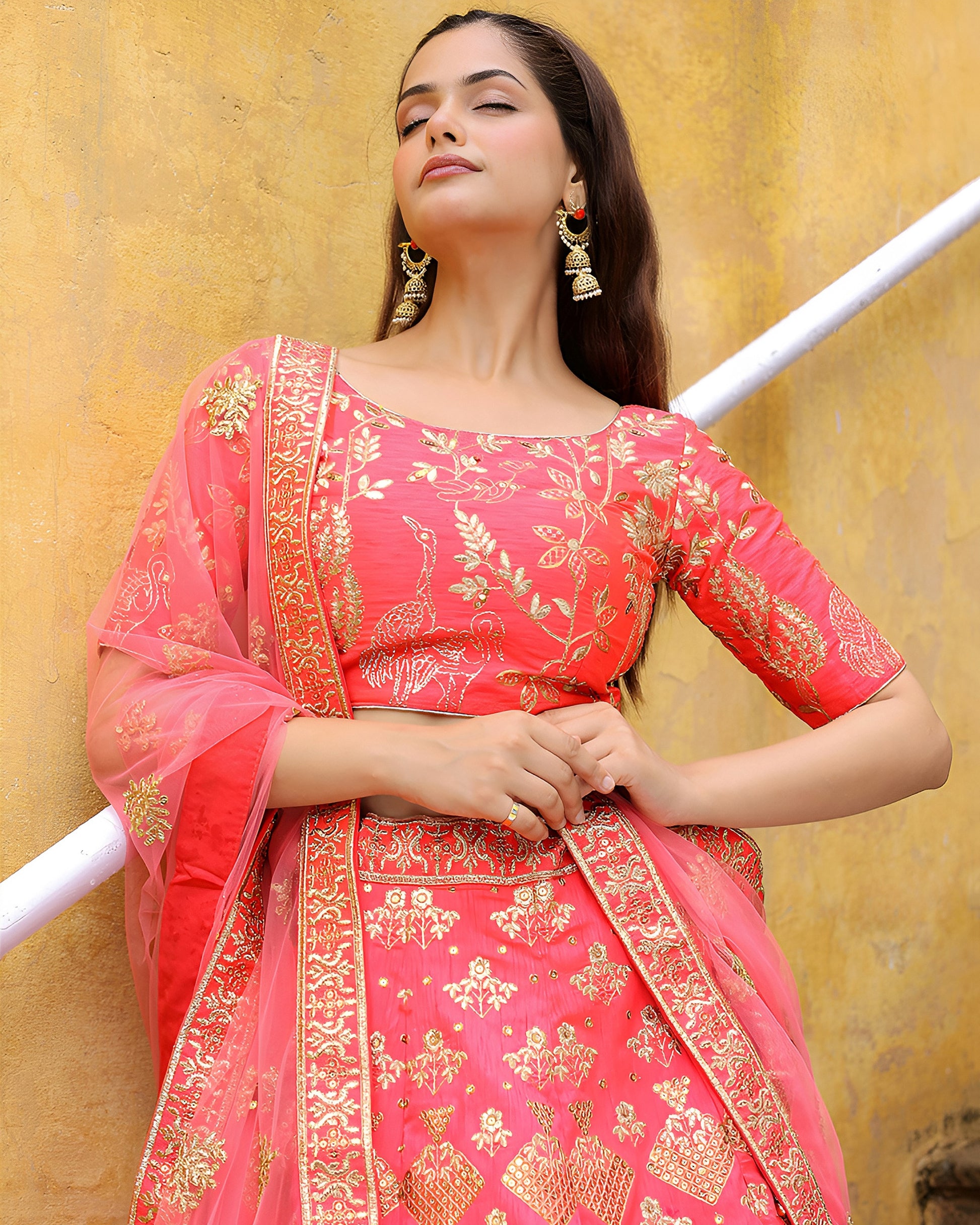 Woman wearing a pink traditional outfit with gold embroidery against a yellow background