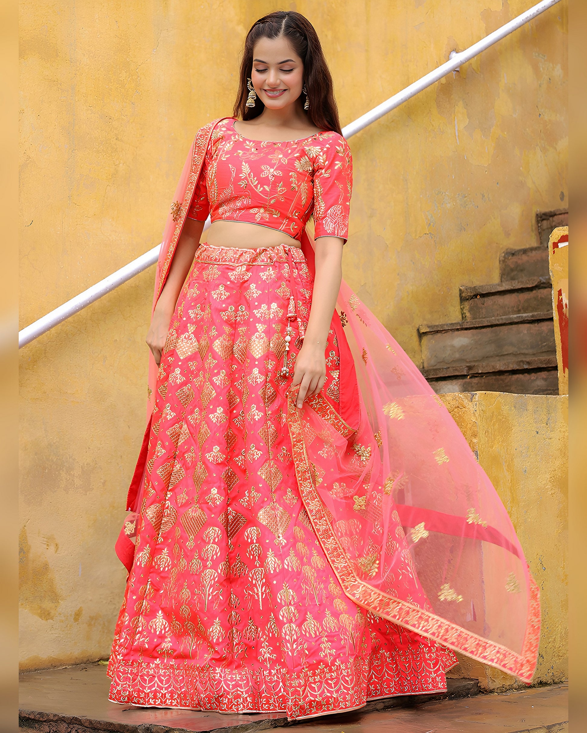 Woman wearing a pink embroidered lehenga with a yellow background