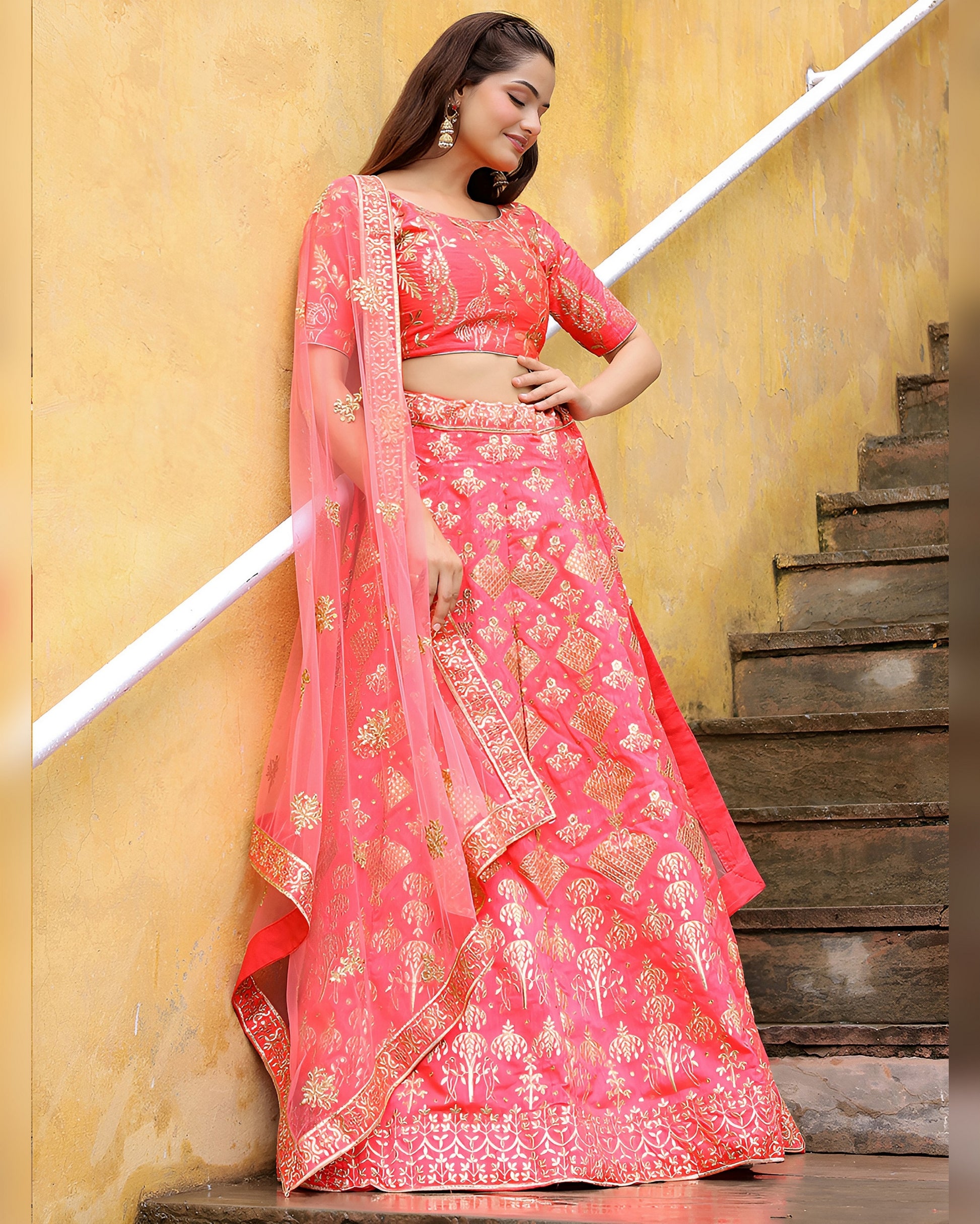 Woman in a pink traditional outfit standing on a staircase with a yellow wall background