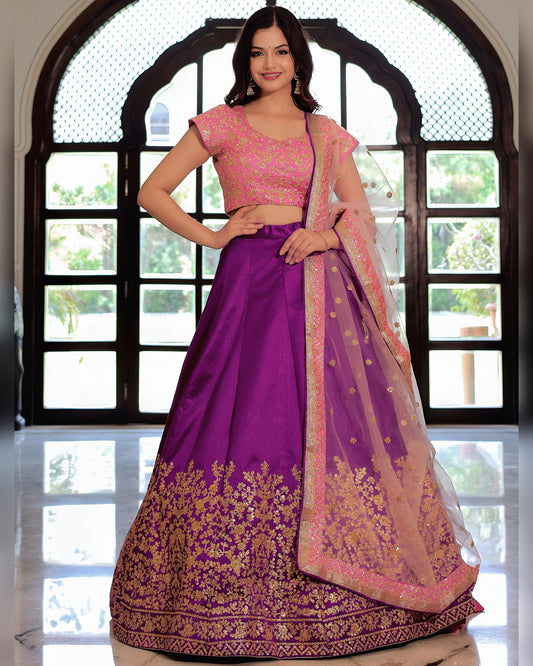 Woman wearing a purple and pink traditional outfit in front of a window.