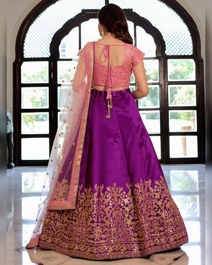 Woman wearing a purple traditional outfit with gold embroidery in front of a large window.