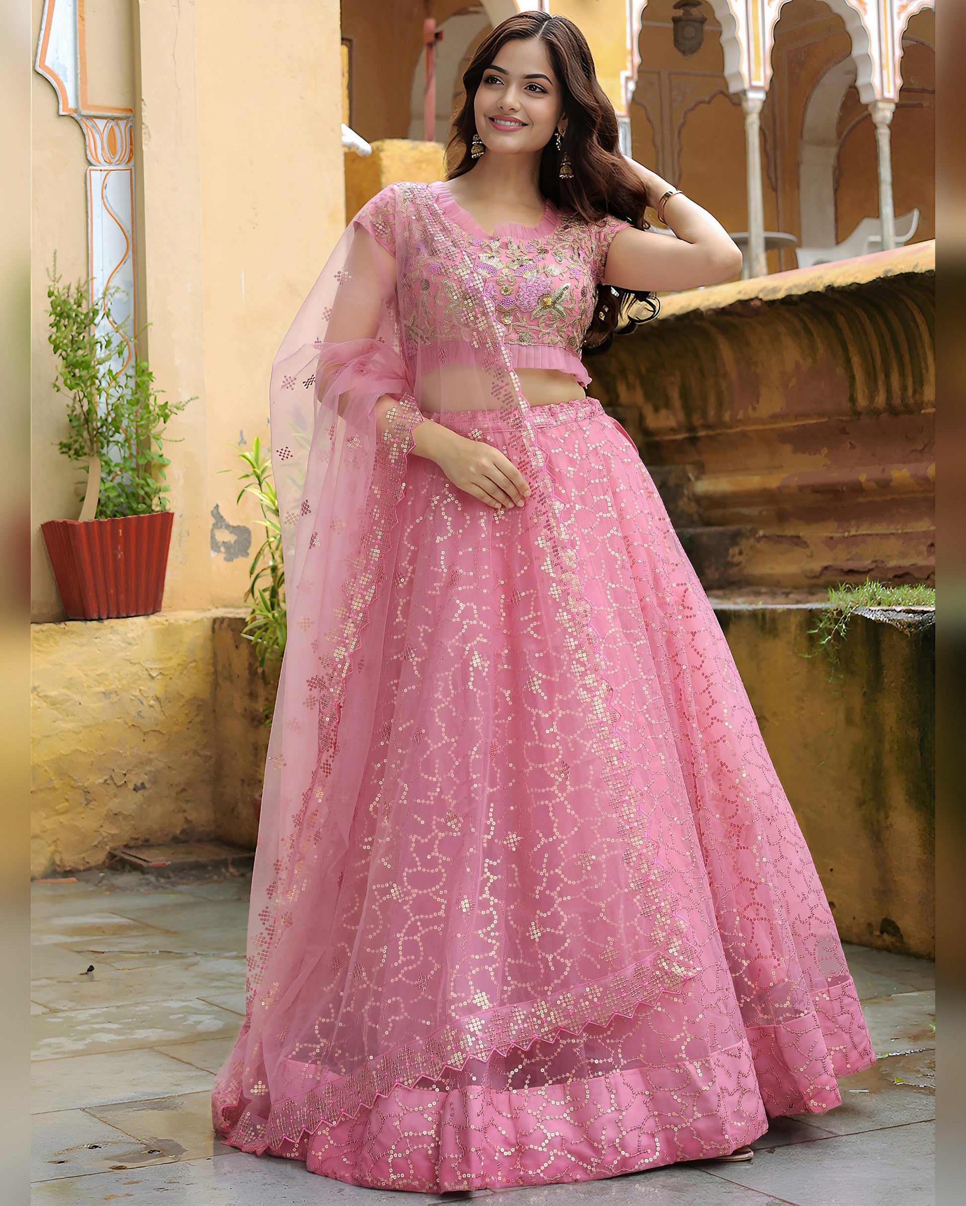 Woman in a pink traditional outfit standing in an outdoor setting.