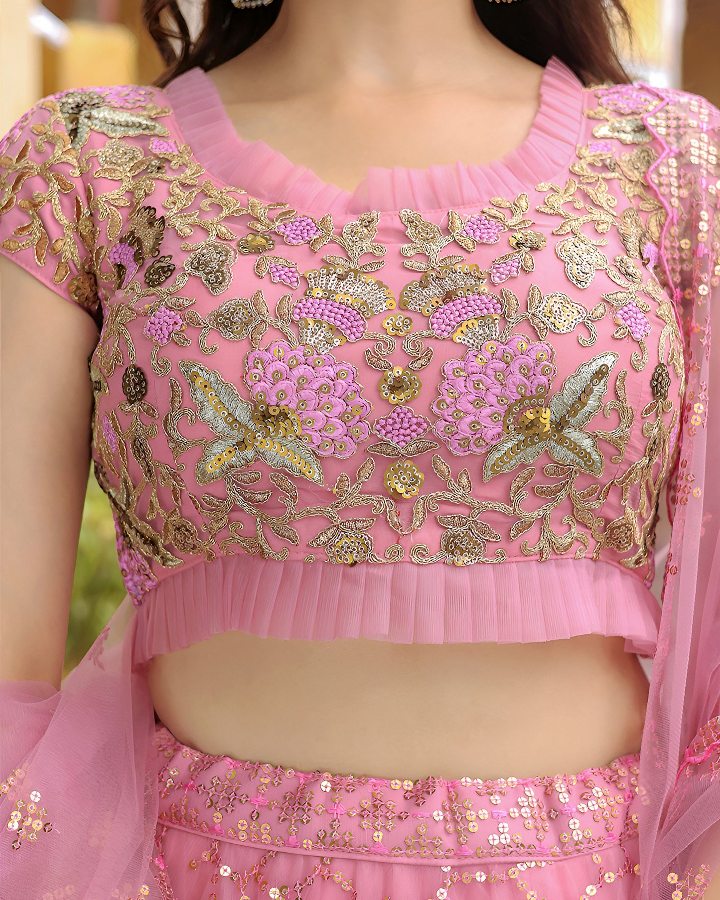 Pink embroidered blouse with gold details on a blurred background