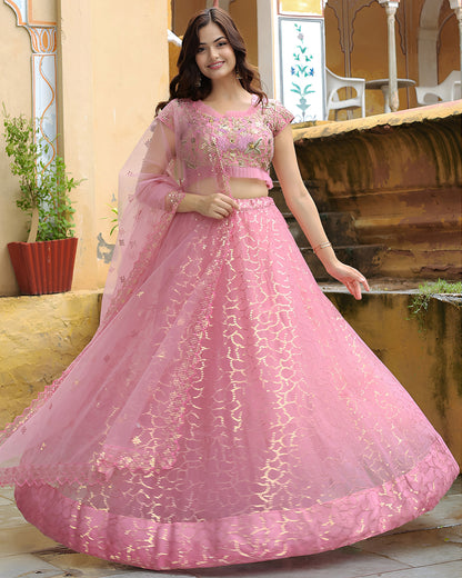 Woman wearing a pink traditional outfit with intricate designs in an outdoor setting.