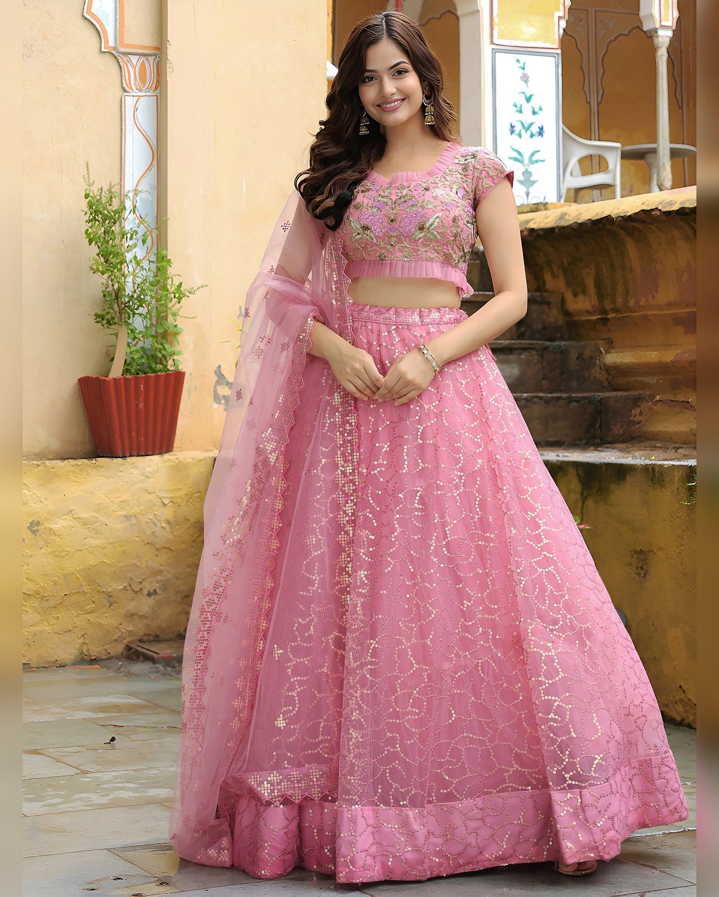 Woman wearing a pink embroidered traditional outfit in an outdoor setting.
