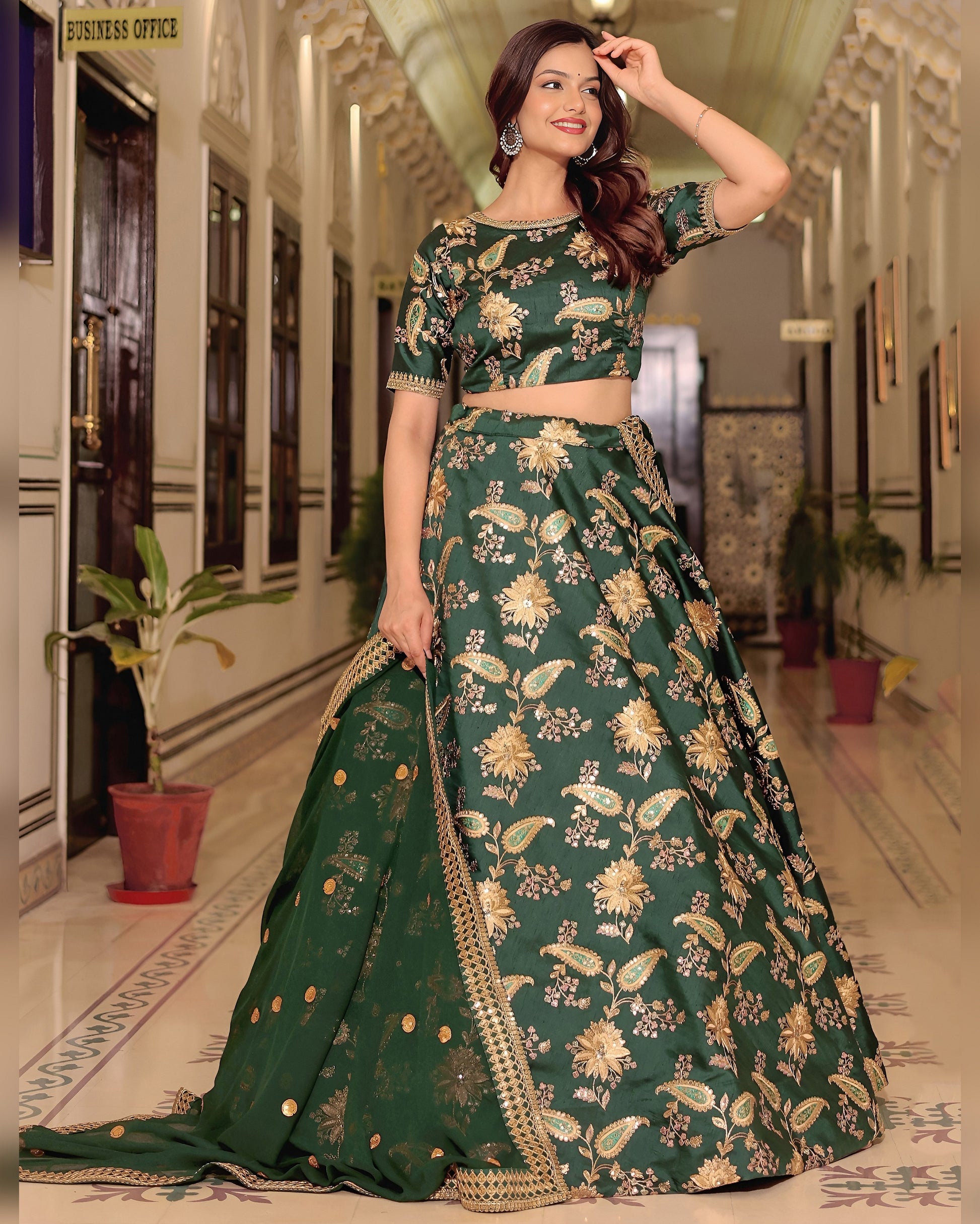Woman wearing a green floral traditional outfit in an indoor setting