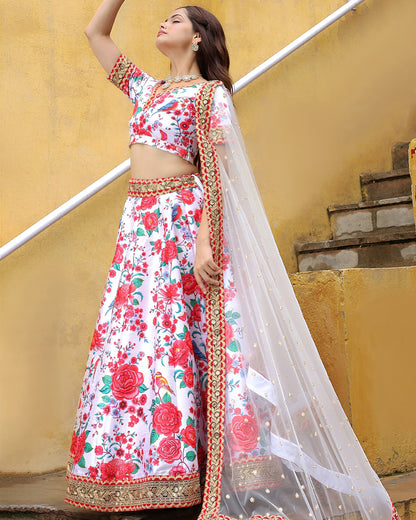 Woman in a floral traditional outfit standing against a yellow wall.