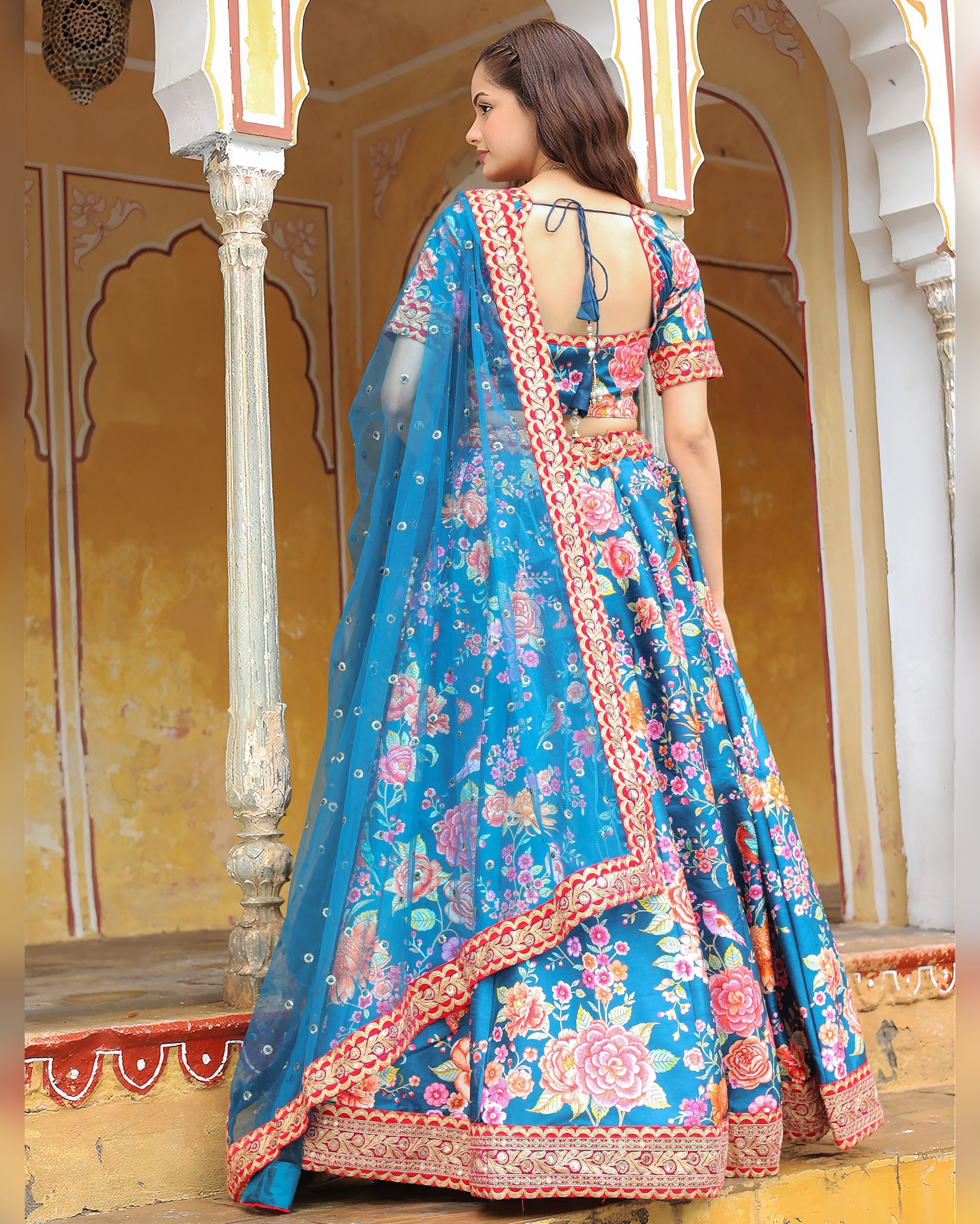 Woman wearing a blue floral saree with a traditional backdrop