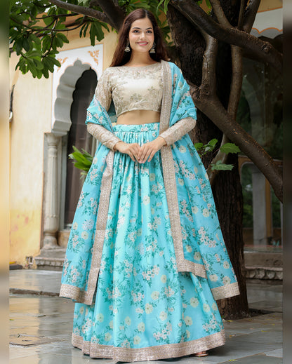 Woman in a traditional outfit with a blue floral dress and beige top, standing outdoors.