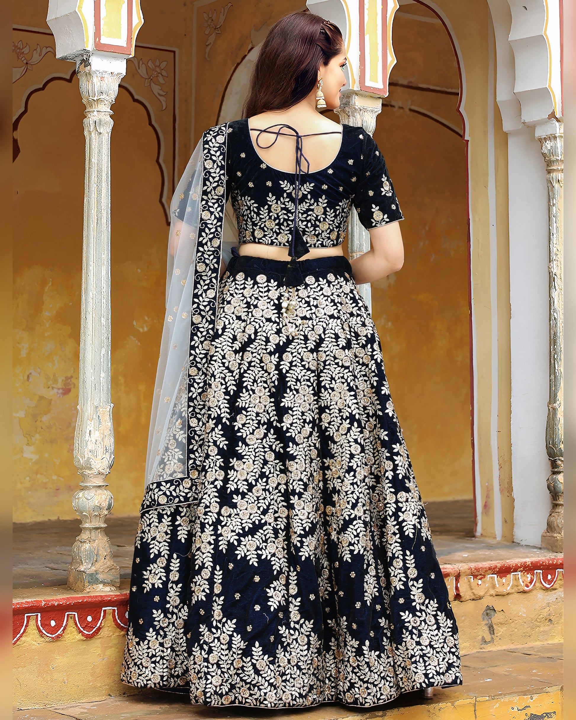 Woman wearing a black and white floral traditional outfit in an ornate setting.