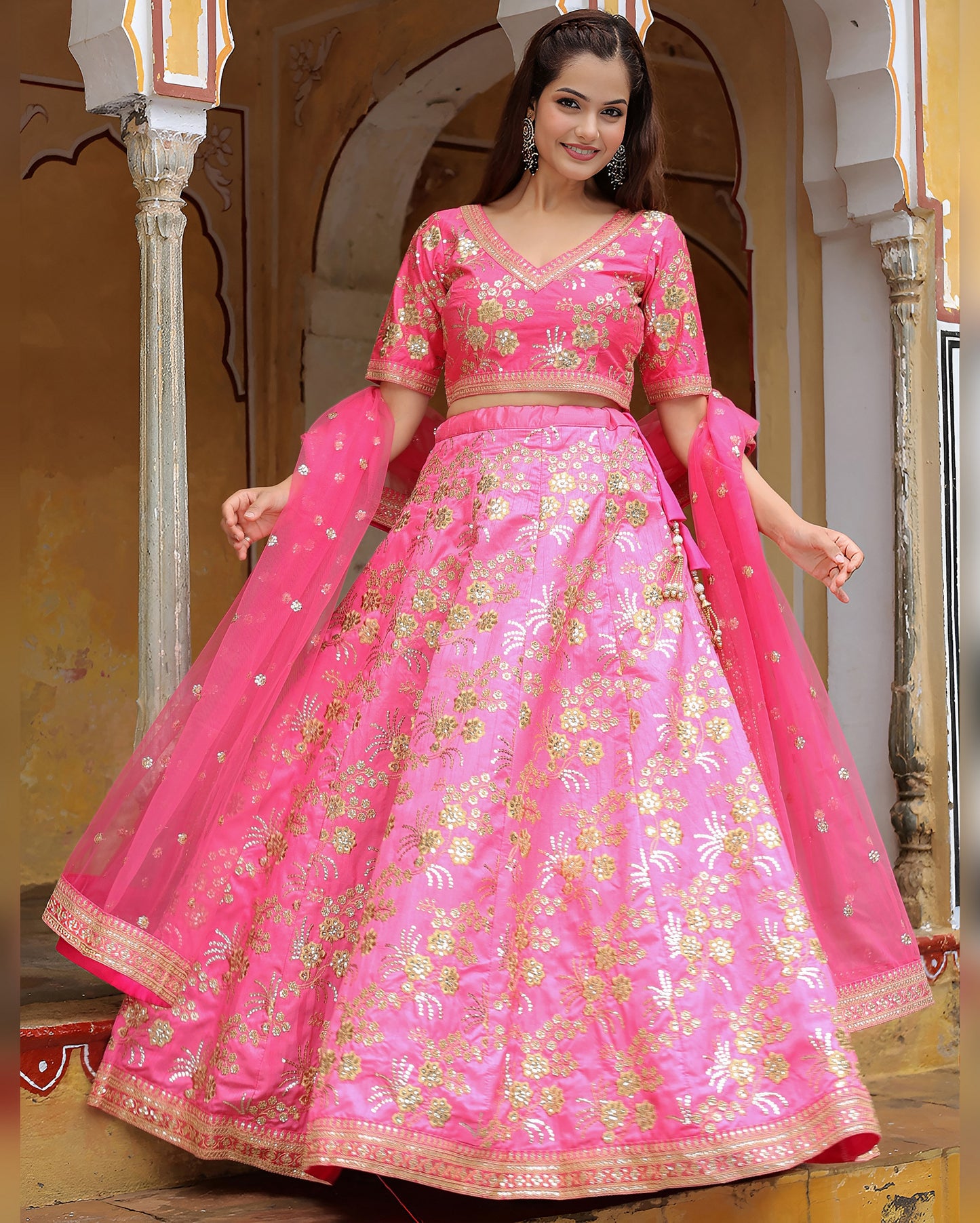 Woman wearing a pink embroidered traditional outfit with a floral design.