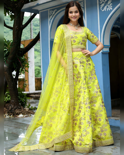 Woman in a bright yellow traditional outfit with floral patterns standing outdoors.