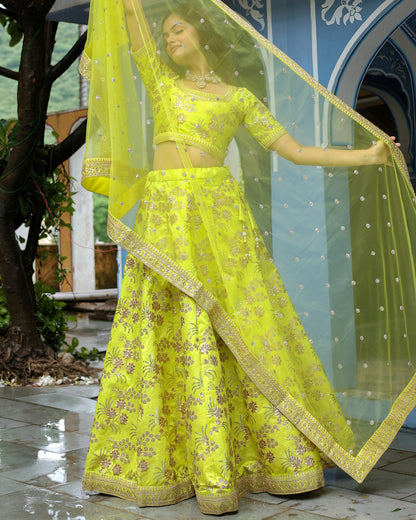 Woman in a bright yellow traditional outfit with floral patterns, standing outdoors.