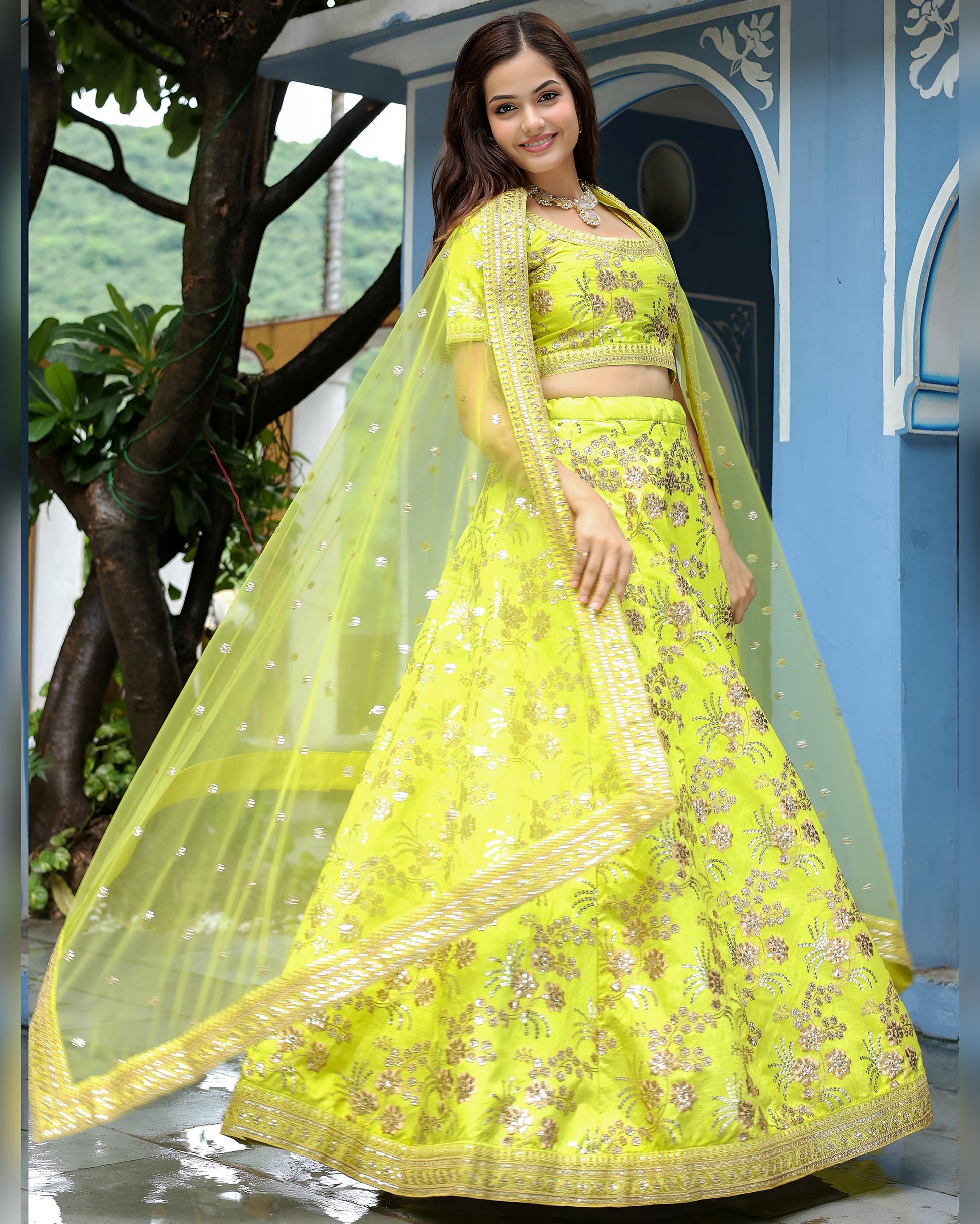 Woman in a bright yellow traditional outfit with a blue architectural background