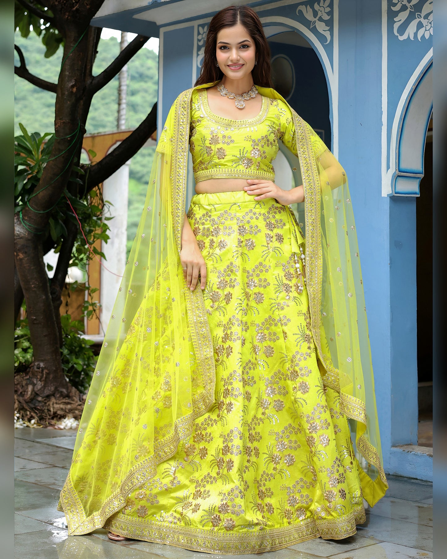 Woman in a bright yellow embroidered traditional outfit standing outdoors.