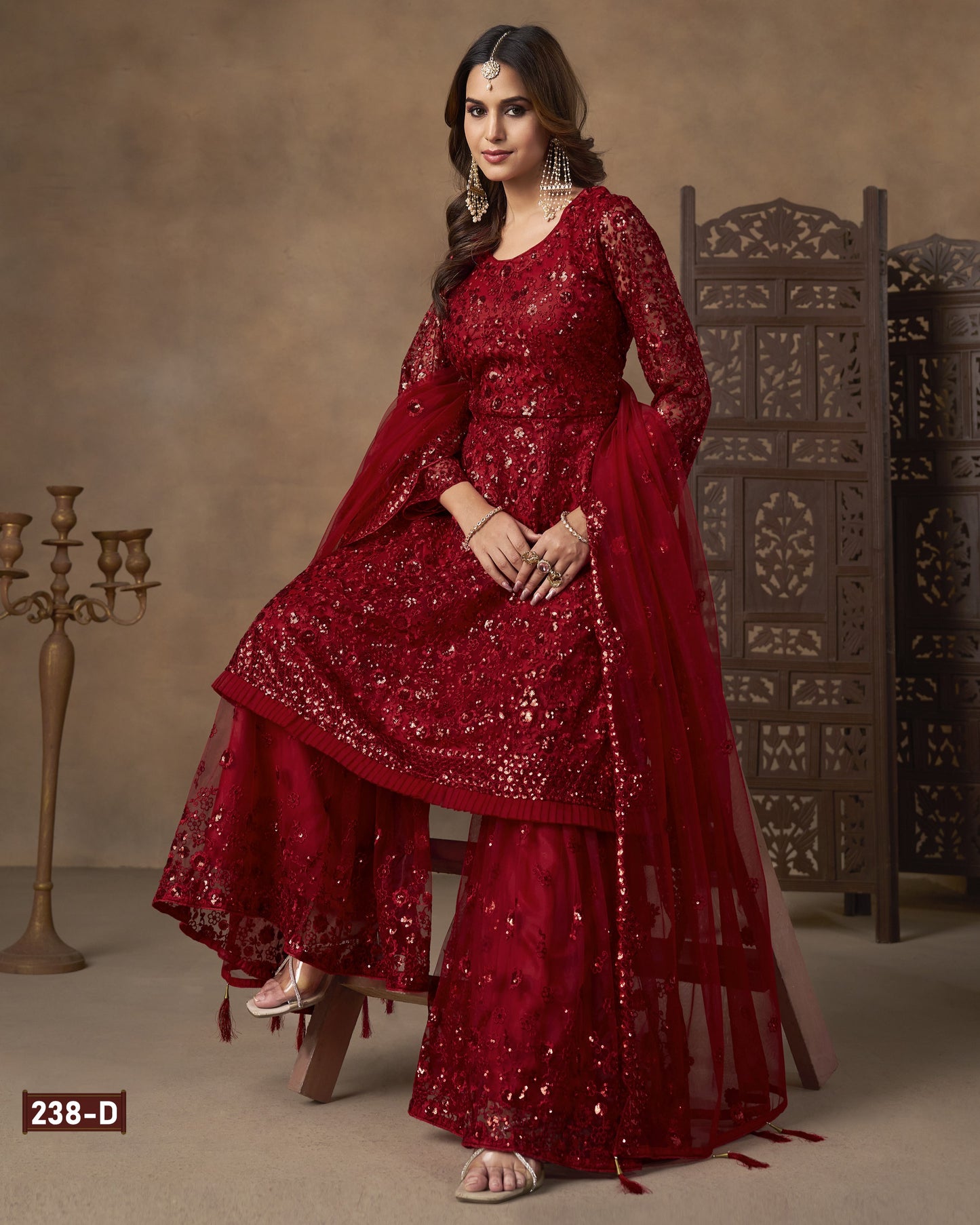 Woman wearing a red traditional outfit with intricate designs against a brown background