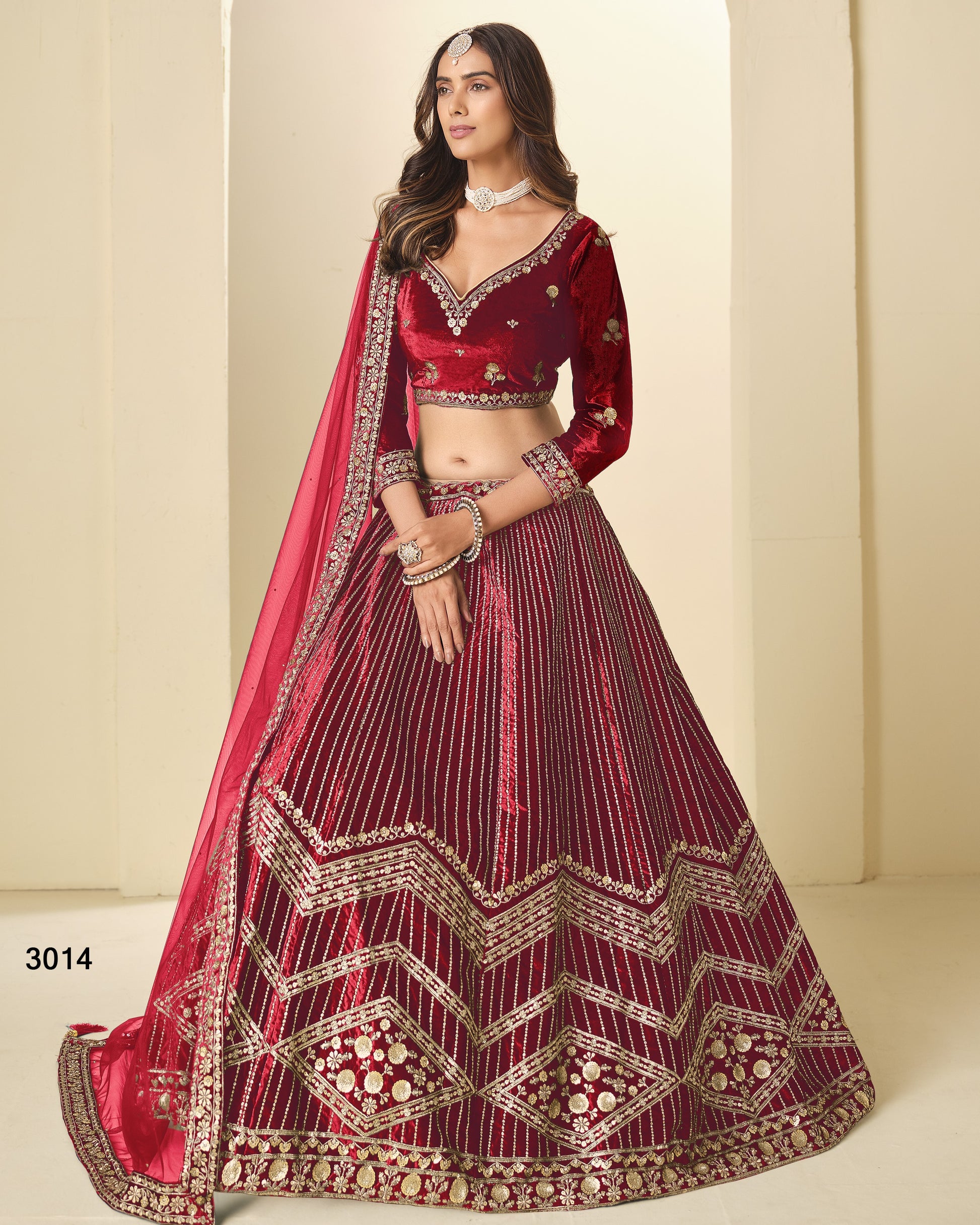 Woman wearing a red and maroon embroidered traditional outfit on a beige background