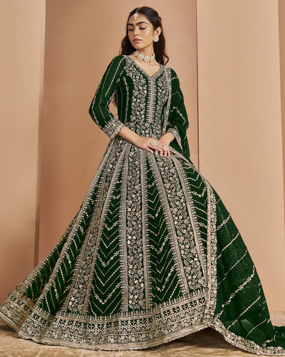 Woman wearing a green and silver embroidered traditional outfit against a beige background