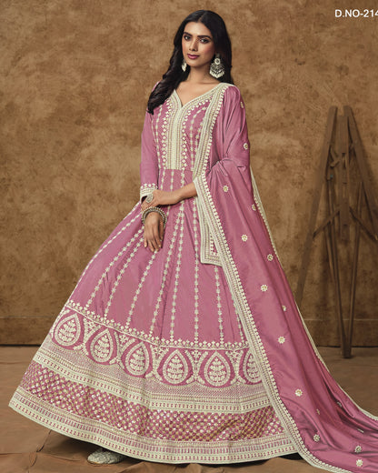 Woman wearing a pink traditional outfit with white embroidery against a brown background