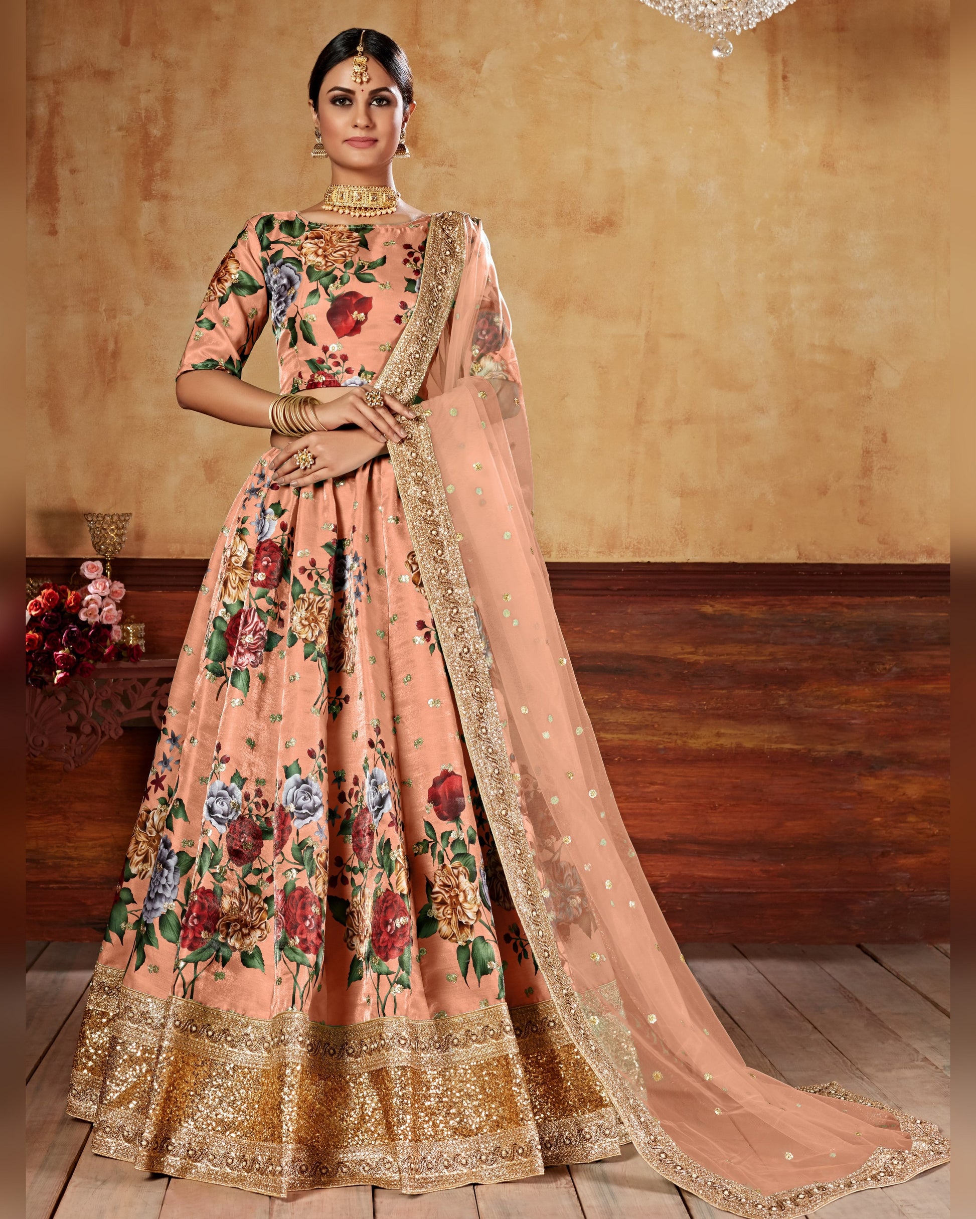 Woman wearing a peach floral traditional outfit with a matching dupatta in a warm-toned room.