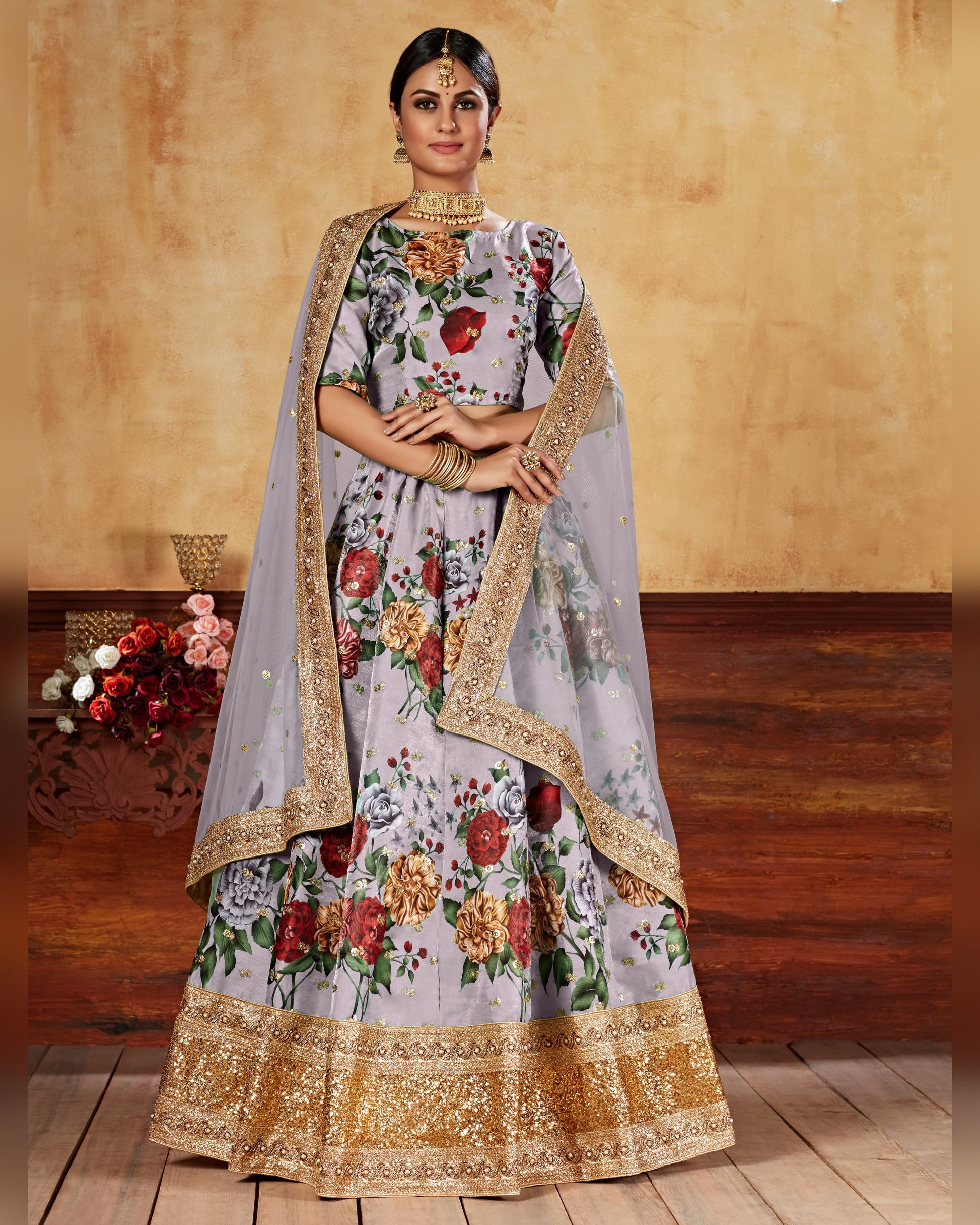 Woman wearing a floral dress with gold accents on a wooden floor.