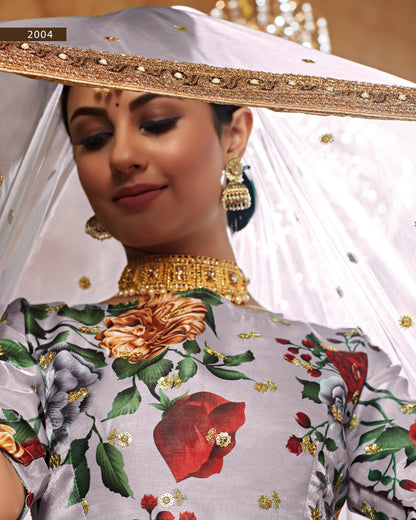 Woman wearing a floral blouse with gold jewelry and a white dupatta.