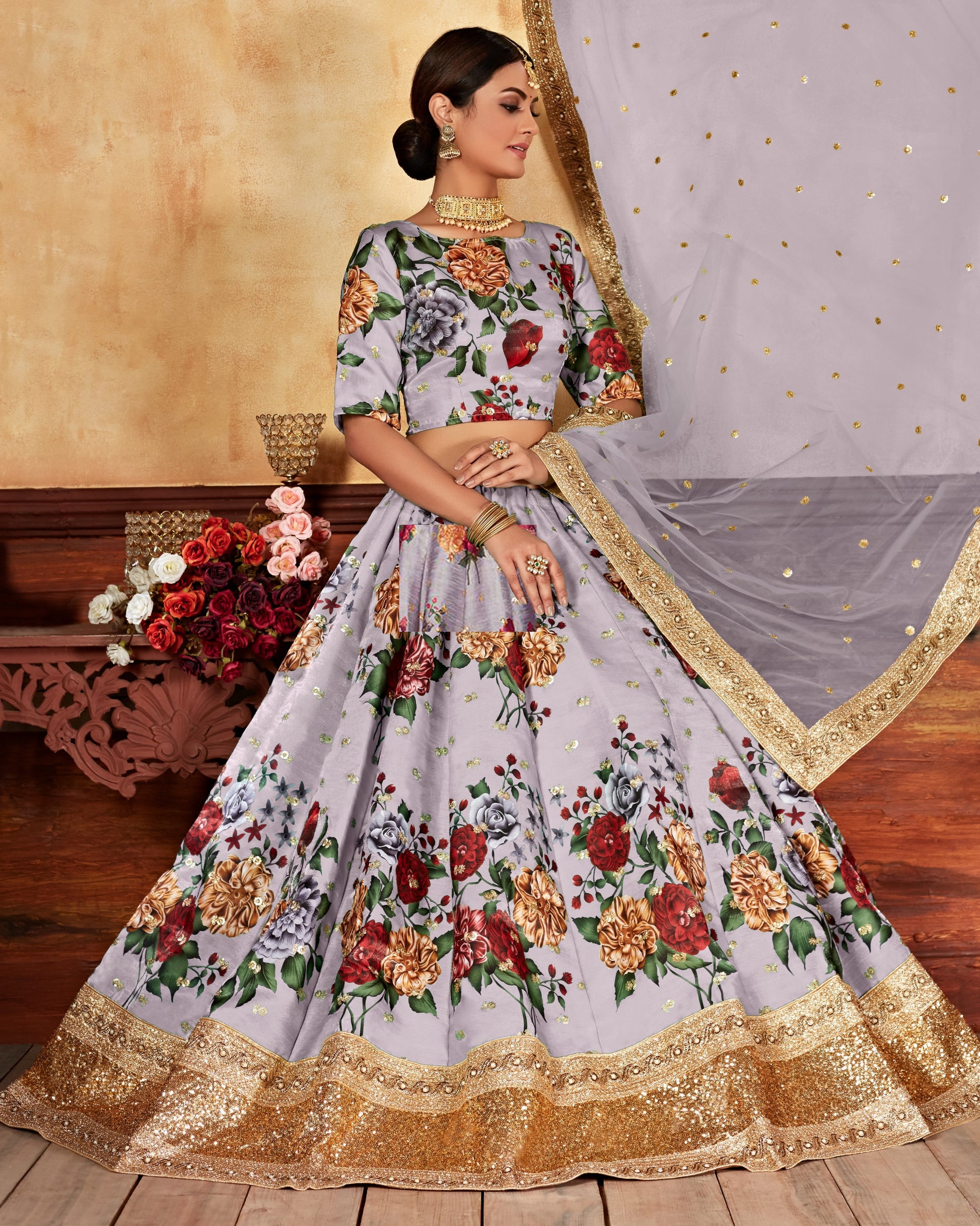 Woman wearing a floral lehenga with a gold border, standing against a neutral background.