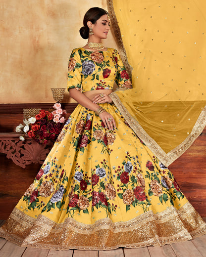 Woman in a yellow floral traditional outfit with a matching dupatta, sitting on a wooden bench.
