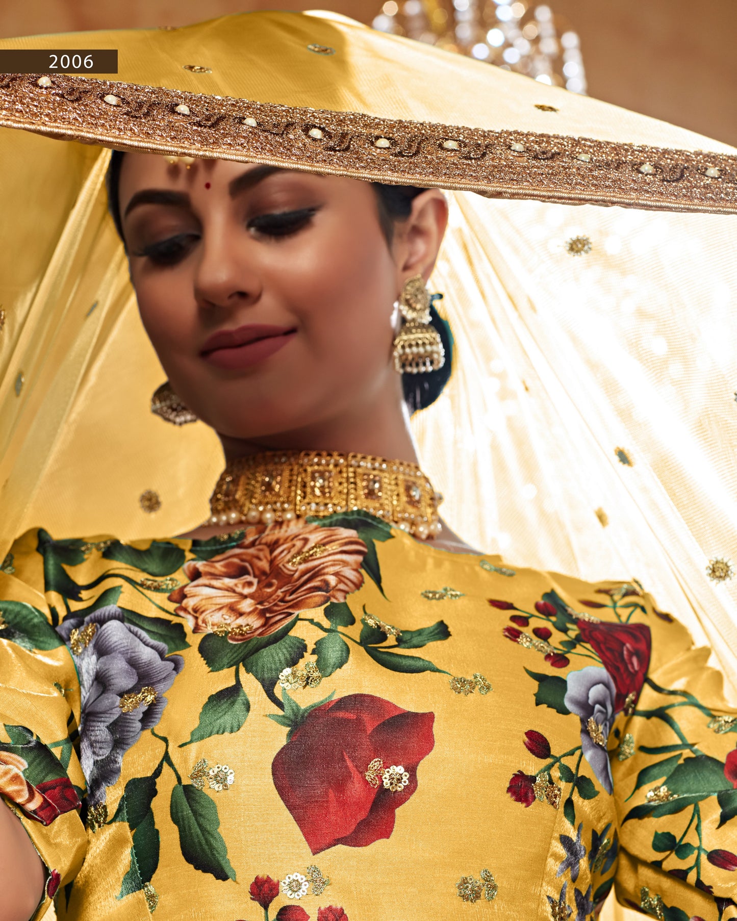 Woman wearing a yellow floral embroidered outfit with gold jewelry, 2006 text visible.