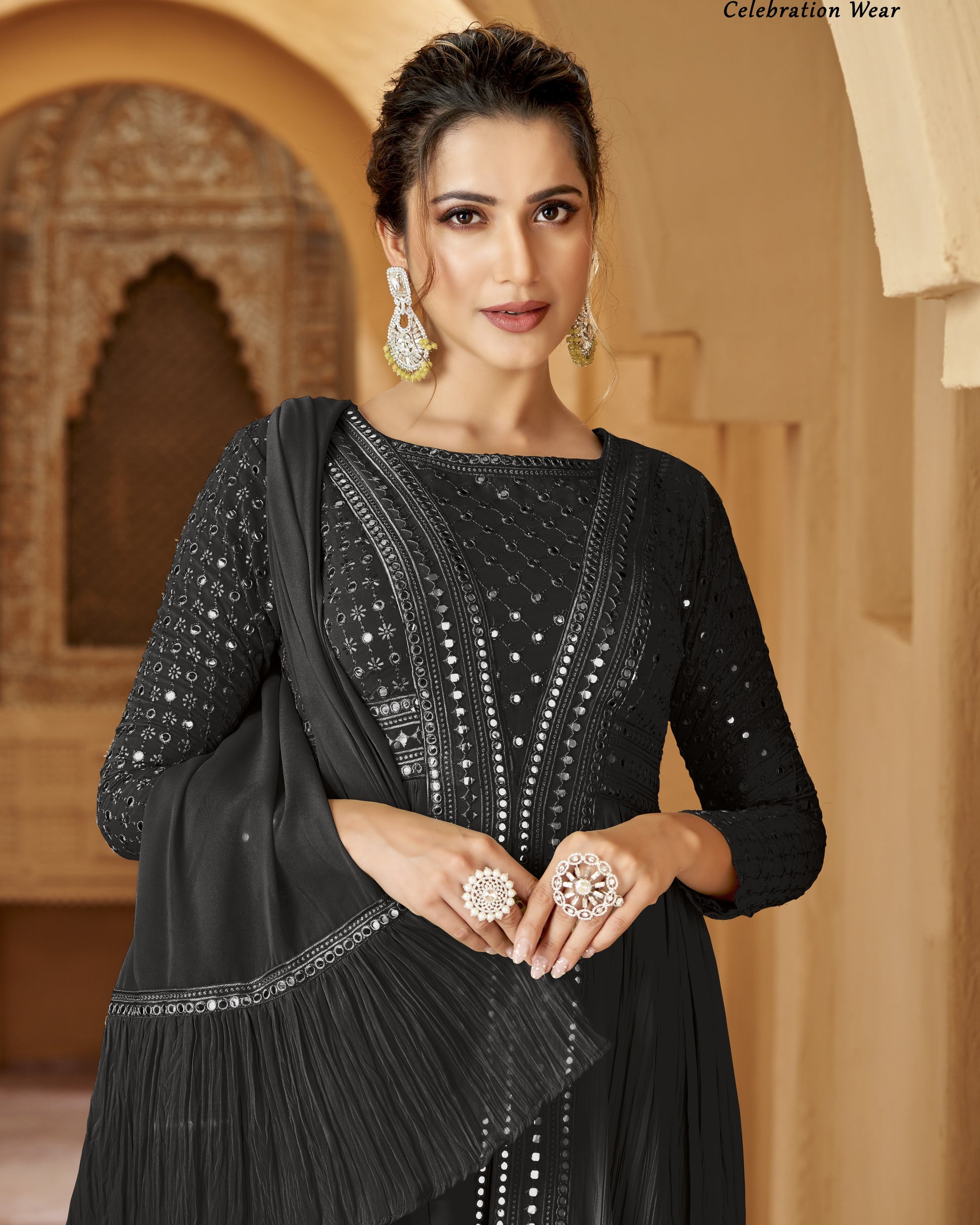 Woman wearing a black traditional outfit with jewelry in a warm-toned architectural setting