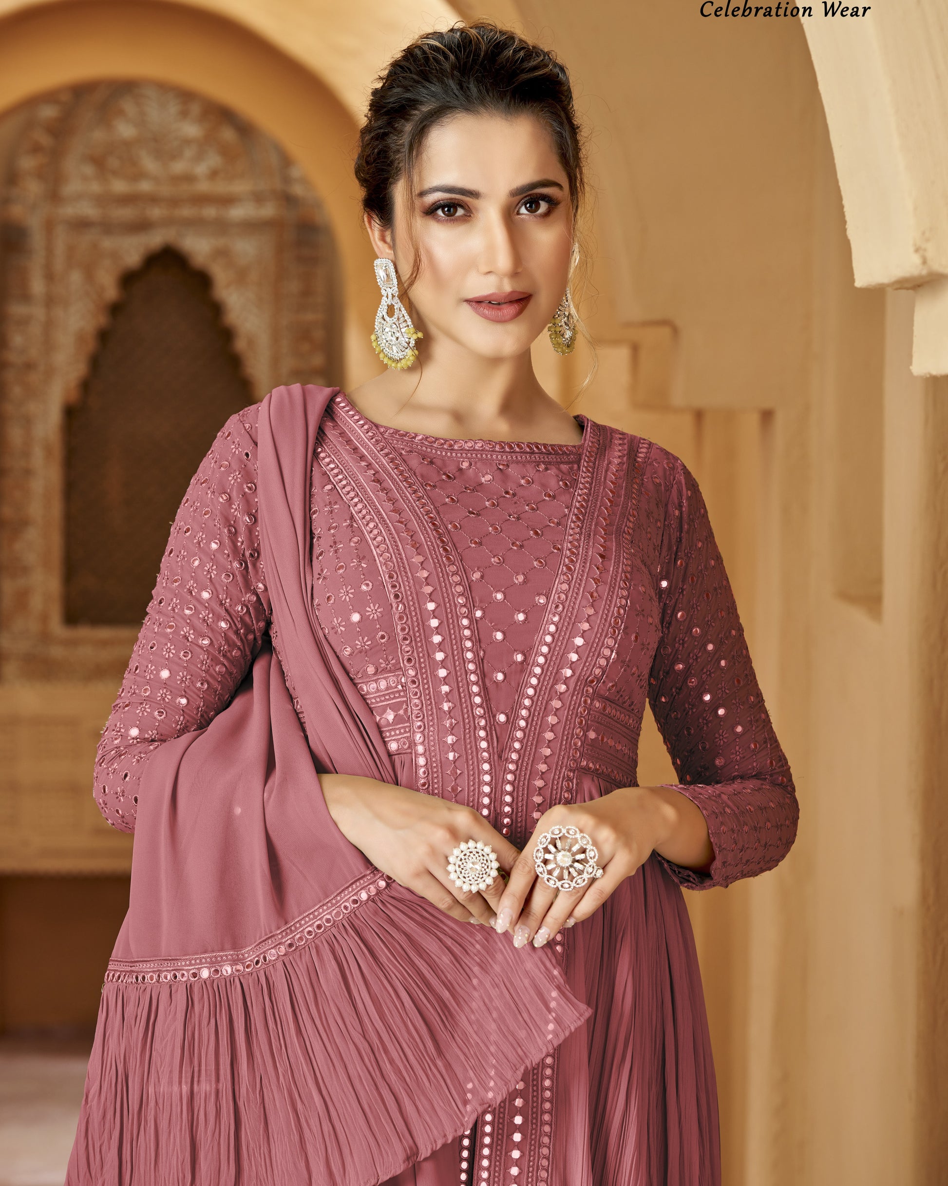 Woman wearing a mauve embroidered outfit with jewelry in a decorative setting