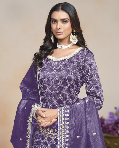 Woman wearing a purple traditional outfit with white embroidery against a neutral background