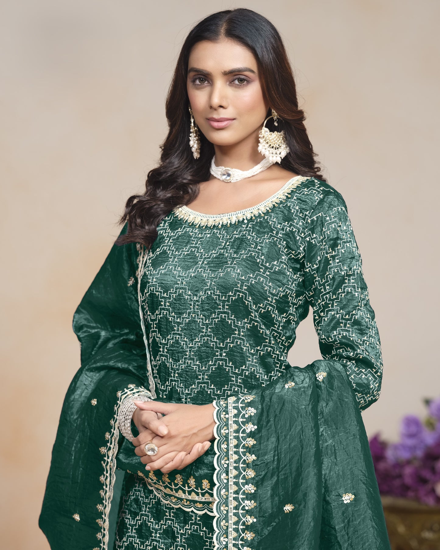 Woman wearing a green traditional outfit with white embroidery against a beige background