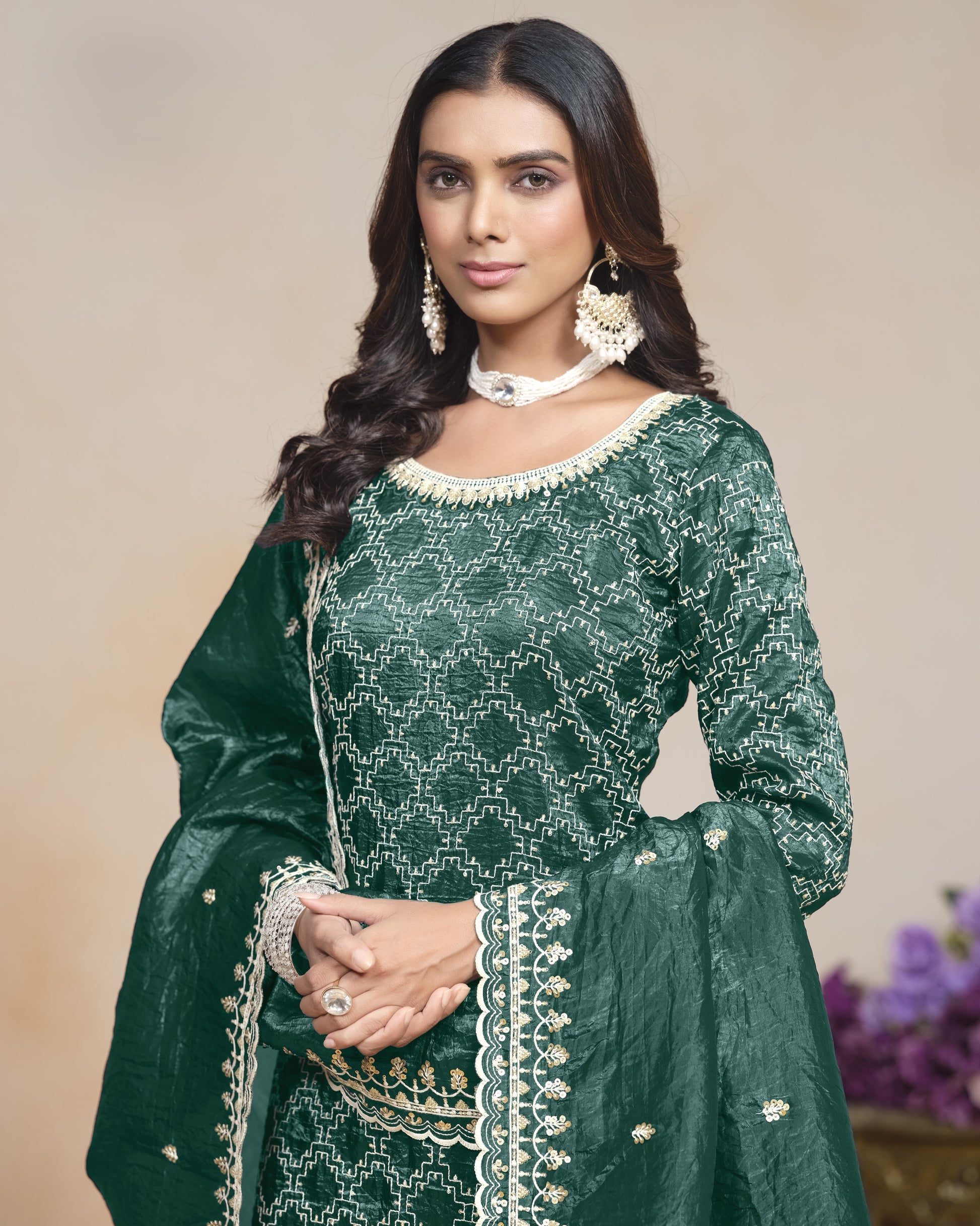 Woman wearing a green traditional outfit with white embroidery against a beige background