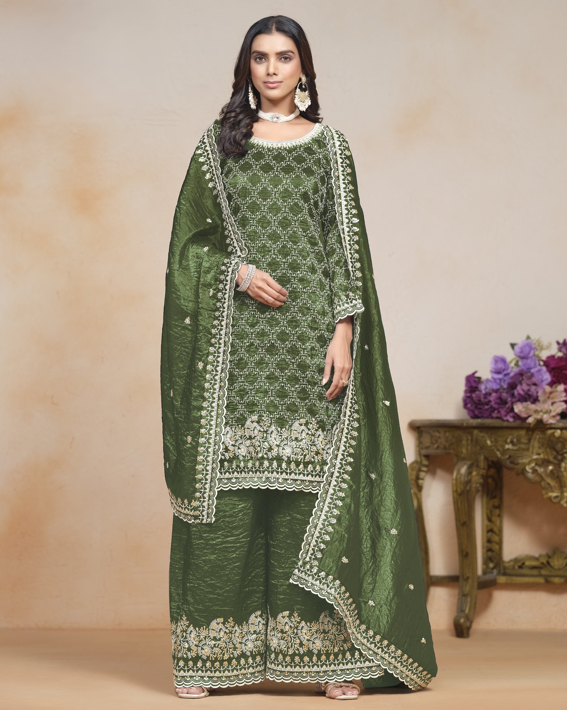 Woman wearing a green embroidered traditional outfit with a plain background