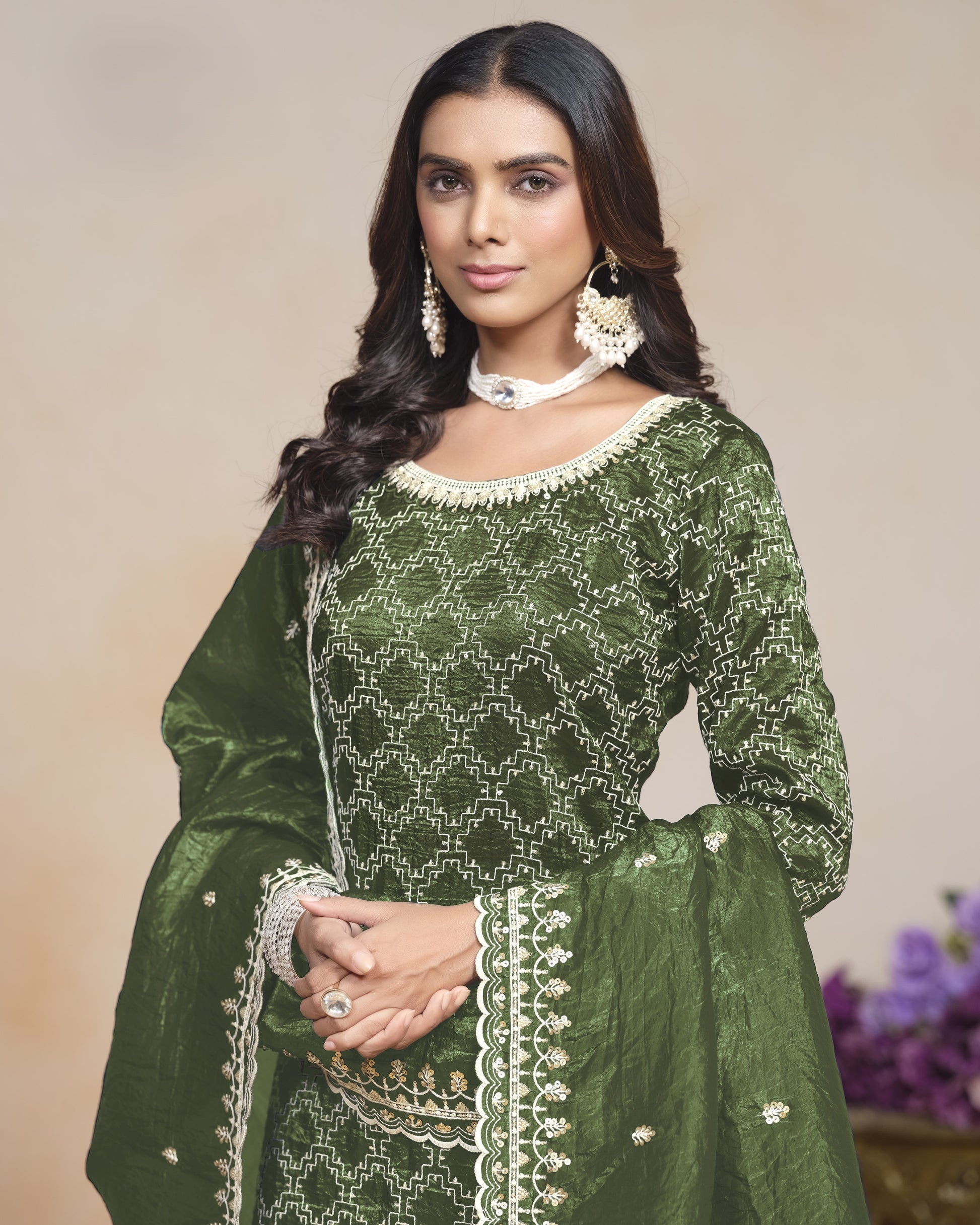 Woman wearing a green embroidered traditional outfit with a neutral background
