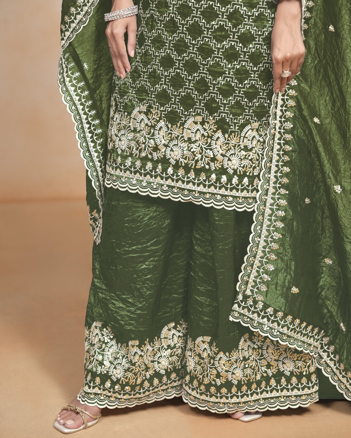 Green traditional outfit with intricate white embroidery on a beige background