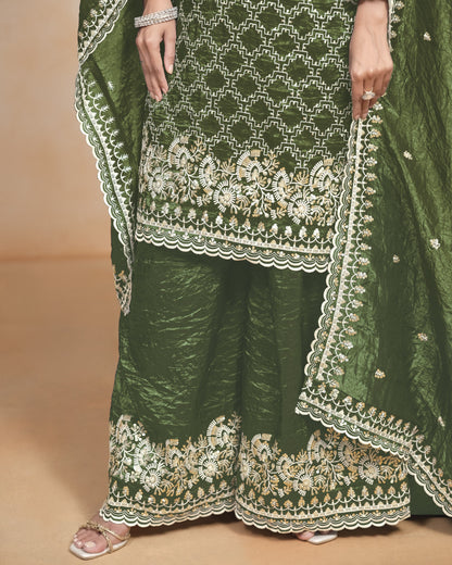 Green traditional outfit with intricate white embroidery on a beige background