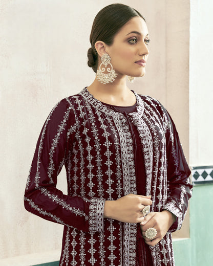 Woman wearing a maroon embroidered outfit with silver details against a light background